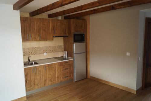 洛索亚河畔布伊特拉戈Puente Viejo de Buitrago CASA ROBLE的厨房配有木制橱柜、水槽和冰箱。