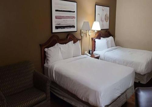 开普吉拉多Auburn Place Hotel & Suites Cape Girardeau的酒店客房,配有两张床和椅子