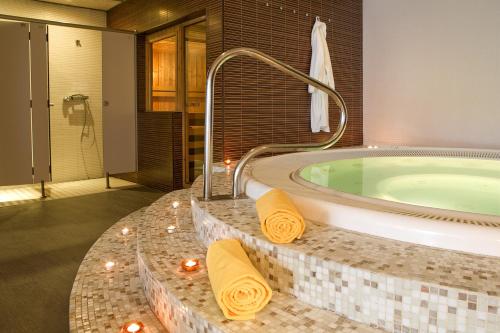 萨洛白玉兰酒店 - 仅限成人的一间带按摩浴缸和黄色毛巾的浴室