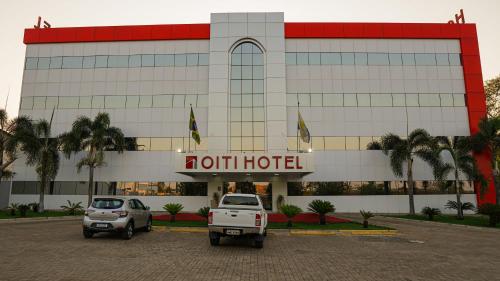 古鲁皮Oiti Hotel - By Up Hotel的两辆汽车停在酒店门前的停车场