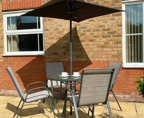 艾尔斯伯里Aylesbury Contractor & Staycation Home的一张桌子、两把椅子和一把伞