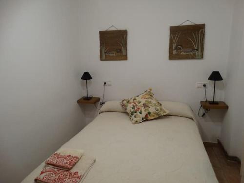 纳赫拉El Herrador的一间卧室配有一张白色床、两盏灯和两张照片