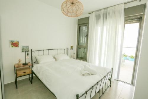 纳哈里亚פנינה באכזיב- מול הים- achzivacation的卧室设有一张白色大床和一扇窗户。