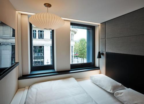 巴黎citizenM Paris Champs-Élysées的一间卧室设有一张床和两个窗户。