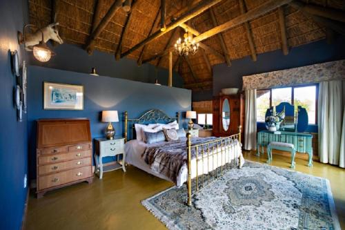 TouwsrivierKamagu Safari Lodge的一间拥有蓝色墙壁的卧室、一张床和一个梳妆台