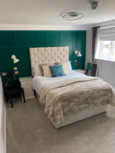 埃文河畔斯特拉特福Stratford House的一间卧室设有一张大床和绿色的墙壁