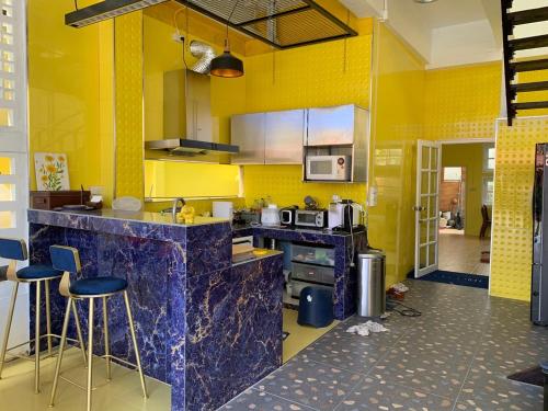 清迈Gumpuju คำปู้จู้的厨房设有黄色的墙壁和带凳子的柜台。