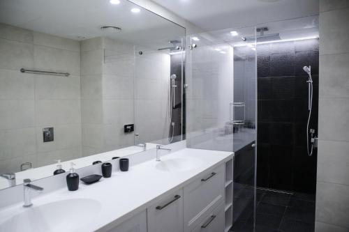 特拉维夫YalaRent Midtown towers TLV的浴室设有2个水槽和带玻璃门的淋浴。