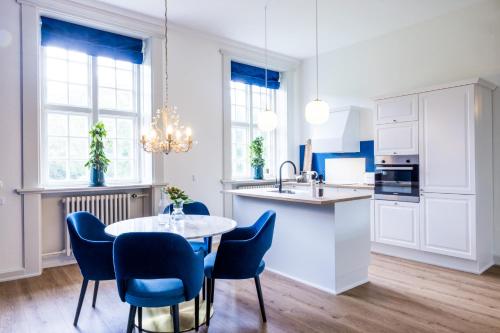 Augustenborg'Gem Suites Luxury Holiday Apartments的厨房配有蓝色的椅子和桌子