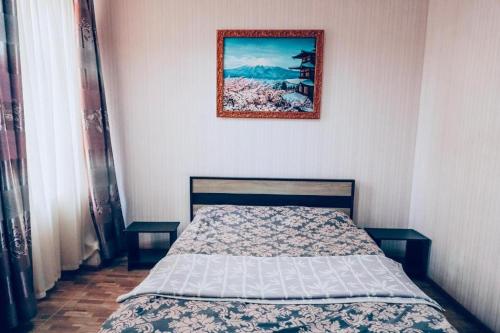 KonotopShangHai Hotel的卧室内的一张床铺,墙上挂着一幅画