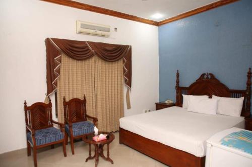 木尔坦Hotel OR Odyssey Residence的一间卧室设有两张床、两把椅子和窗户。
