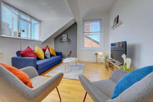 利明顿温泉Leamington Spa Warwick Place Apartments的客厅配有蓝色的沙发和两把椅子