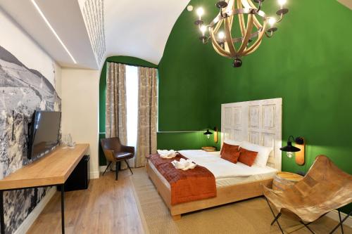 埃格尔1552 Boutique Hotel的绿色卧室配有1张床、1张书桌和吊灯