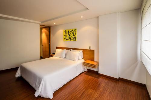 波哥大旅行者奥博里斯科公寓的卧室配有一张白色的大床,铺有木地板