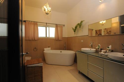 苏莎亚Instyle Residences at Infiniti Blu的带浴缸、两个盥洗盆和浴缸的浴室。