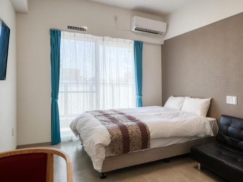 那霸BiBi Hotel NAHA KUME的卧室配有床、椅子和窗户。