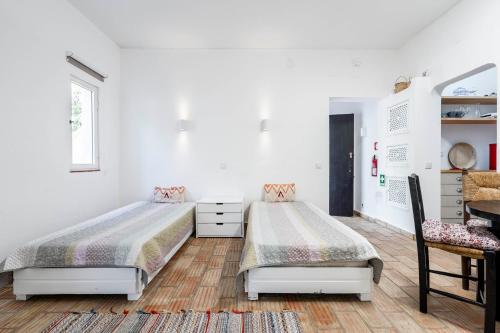 塔维拉Apartamento 157, Pedras d’el Rei的卧室设有两张床,拥有白色的墙壁和木地板