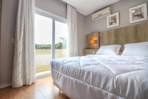 格拉玛多Pousada Bella Viena的卧室设有白色的床和大窗户
