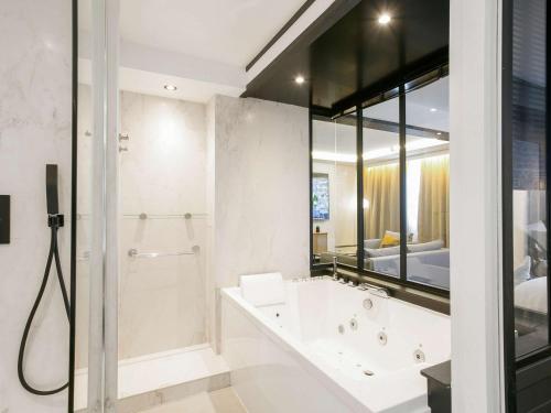 梅里尼亚克波尔多机场美居酒店的设有带浴缸和淋浴的浴室。