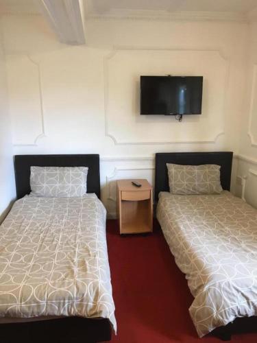 哈特菲尔德Hatfield SAVE-MONEY Rooms - 10over10 for PRICE!的一间卧室设有两张床,墙上配有电视。