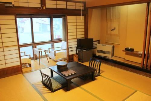 ŌwaniHistorical Ryokan SENYUKAN的客厅配有桌椅和电视。