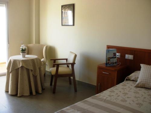 卡拉德费斯特拉特Ballesol Costablanca Senior Resort mayores de 55 años的卧室配有1张床、1张桌子和1把椅子