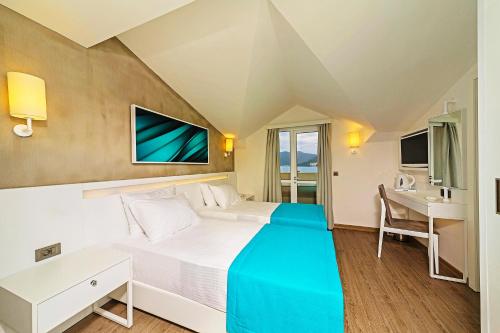 马尔马里斯Poseidon Hotel - Adult Only的配有一张床和一张书桌的酒店客房