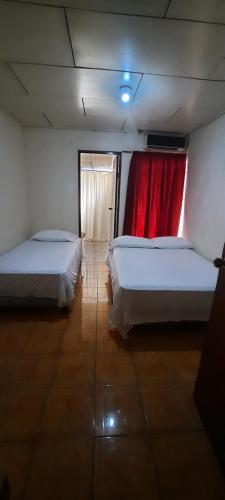 玉米岛Hospedaje Tropical Dreams的一间设有两张床和红色窗帘的房间