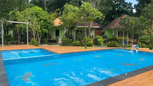 坤西育府Somrudee Resort的一座大蓝色游泳池,位于房子前