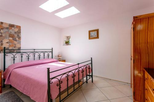 StrianoCasa Oasi della Pace的一间卧室配有一张带粉红色床罩的床
