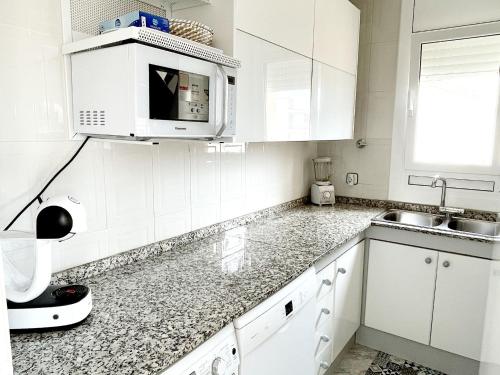 埃勒凡达尔Open Sky, Apartamento con solárium privado y barbacoa的白色的厨房配有白色的橱柜和微波炉
