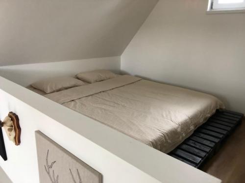 斯克伦达Skrundas namiņš的白色客房的一张床位,配有床罩