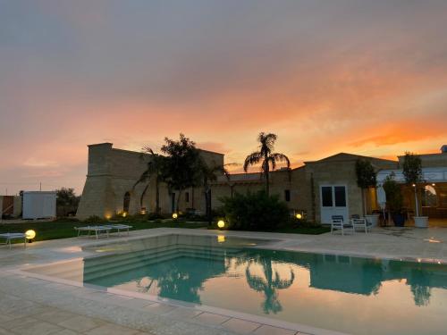 纳尔多PODERE CARAFA的一座享有日落美景的建筑前的游泳池