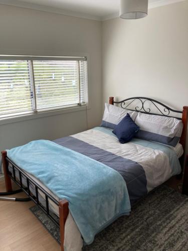 AlonnahBruny Ocean Cottage的一间卧室配有一张带蓝色毯子的床和两个窗户。