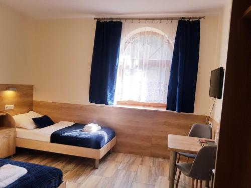 BrzeźnoGościniec Piast Hotel i Camping的一间卧室配有床和蓝色窗帘的窗户