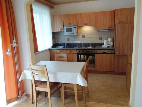施特罗布尔Appartements Edda的厨房配有桌子、两把椅子、一张桌子和一台微波炉