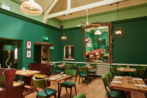 伍德斯托克金斯阿姆斯酒店的餐厅拥有绿色的墙壁和木桌及椅子