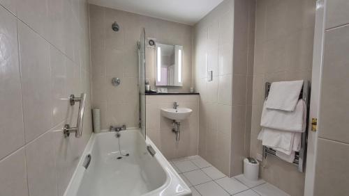 赖盖特Reigate Manor Hotel的白色的浴室设有浴缸和水槽。