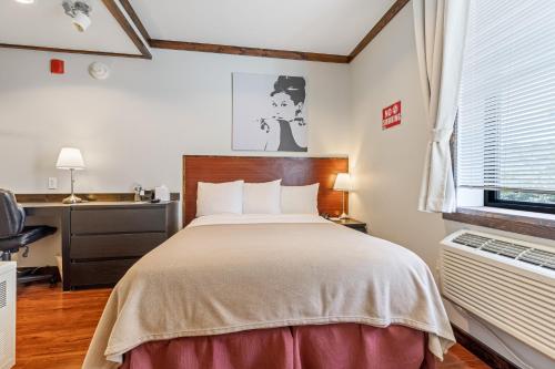 皇后区里克酒店的一间卧室配有一张床、一张书桌和一个窗户。