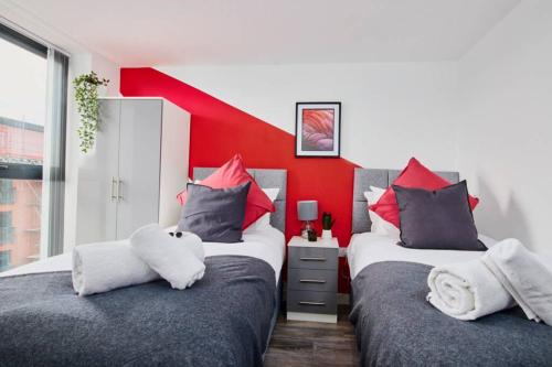 曼彻斯特Stylish 2 Bed Apartment with Free parking, close to City Centre by Hass Haus的红色墙壁的客房内的两张床