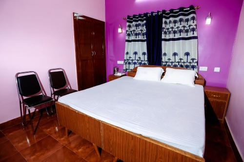巴特那Hotel Virasat Retreat的一间卧室配有一张大床和两把椅子