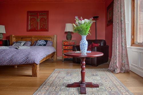 爱丁堡Netherbrae的一间卧室,配有一张床,桌子上放着花瓶