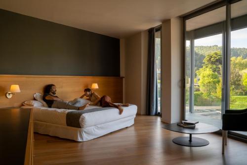 圣弗鲁克托索-德巴赫斯圣贝尼特酒店的两人坐在酒店房间的床边