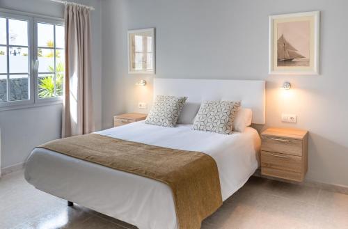 卡门港Villas Maribel Pocillos的卧室设有一张白色大床和一扇窗户。