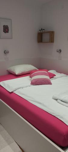 卢布尔雅那Apartment EMA的一张配有粉色和白色床单及枕头的大床