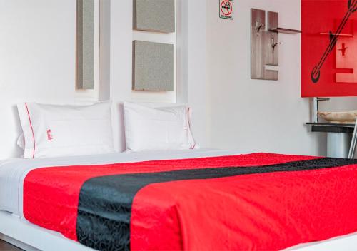 Las ÁnimasHotel Puente Grande的卧室配有红色和黑色的毯子,位于床上