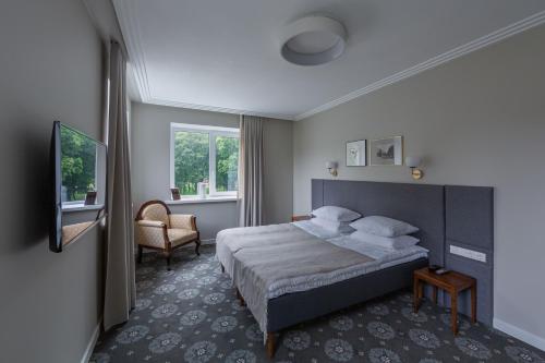 希奥利艾Park Hotel Šiauliai的配有一张床和一把椅子的酒店客房