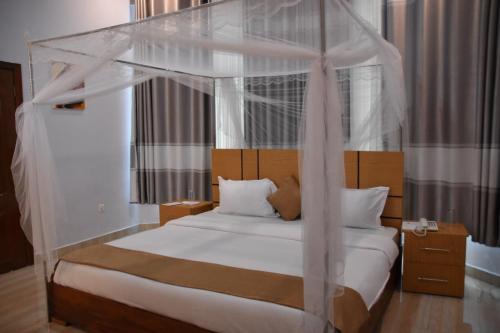RwumbaChimpanzee Lodge的卧室配有带白色床单和枕头的天蓬床。