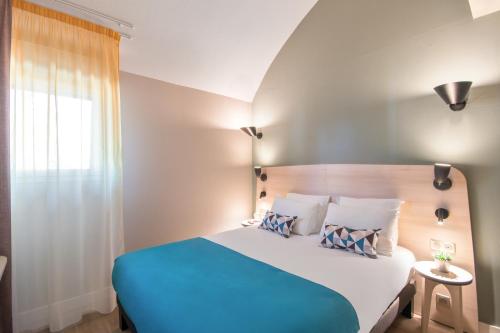 蒙彼利埃Appart'City Confort Montpellier Saint Roch的卧室配有蓝色和白色的床和窗户。