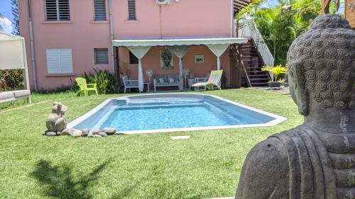 圣弗朗索瓦Villa Rosa Karibella的一座带游泳池的房子的院子内的雕像